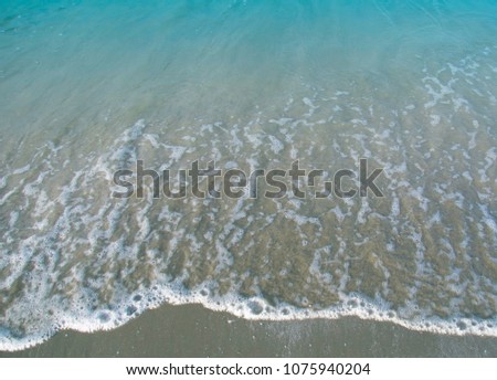 Soft wave water of sea shore on sandy beach with foam / copy space and background