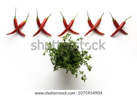 Red hot little chili peppers pattern in form of letter X and green thyme isolated on white background. Top view. Flat lay