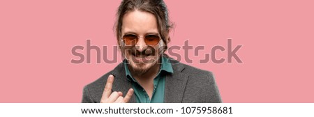 Handsome young man making rock symbol with hands, shouting and celebrating