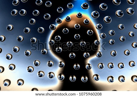 Drops of water on a glass surface with reflection of an abstract silhouette in cold colors.
