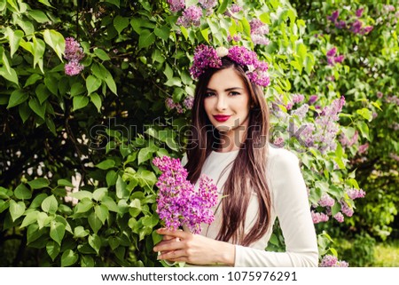 Smiling woman with flowers outdoors. Beautiful brunette girl with long healthy hair and make up