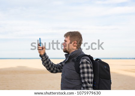 Traveler man taking photos to the beach with smartphone camera on summer travel vacation or hike to the coast.