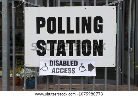 British election polling station sign with disabled access hanging on fence in London, UK