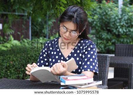 woman sitting on the park bench and reading a book.