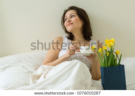 Middle aged woman is pleased with gift, bouquet of flowers