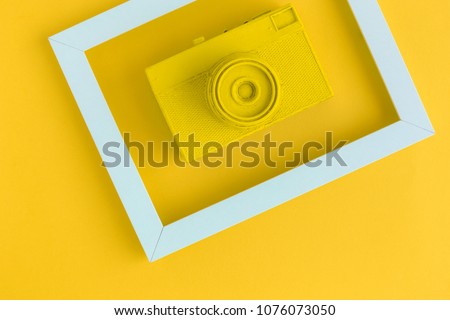 Retro film photo camera colored in yellow with photo frame minimal abstract creative concept