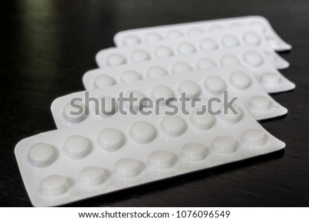 White aluminium blister pill pharmacy medicine health care template concept. White drug on isolated black wooden board background. Medicament blister pack with pills