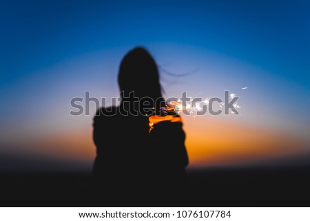 Silhouette of a girl on a sunset with fireworks