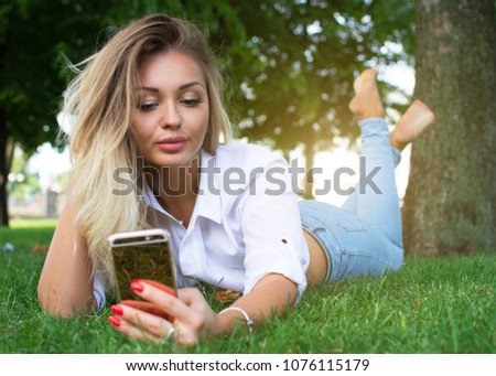Portrait of a girl in a white shirt doing selfie in a park. Free space.