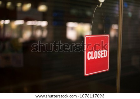 Shot of a red color closed sign hanging from inside a glass sliding door
