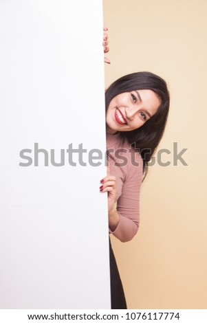 Young Asian woman show victory sign with blank sign on beige background