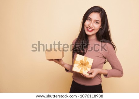 Young Asian woman open a golden gift box on beige background