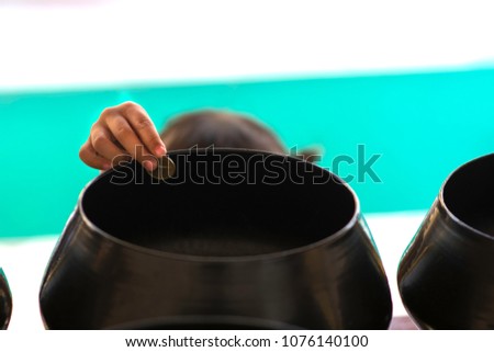 Close up little girl hand give coine to offerings in a Monk's alms bowl.