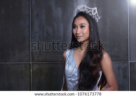 Portrait of Miss Pageant Beauty Contest in sequin Blue Evening Ball Gown long dress with Diamond Crown, Asian Woman fashion make up black hair style, studio lighting dark background copy space