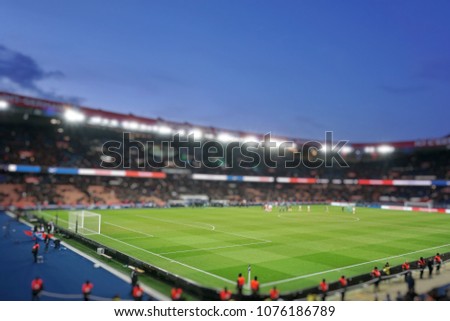Blurred background of football players playing and soccer fans in match day on beautiful green field with sport light at the stadium.Sports,Athlete,People Concept.Paris saint-germain.France. Royalty-Free Stock Photo #1076186789