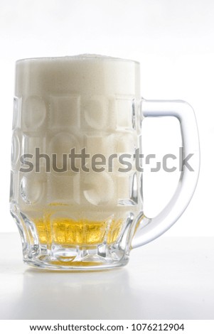 Beer mug. Mug of light fresh beer with a lot of foam on light background
