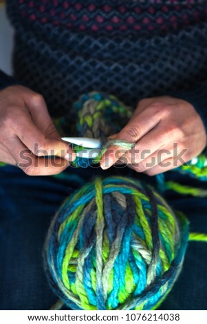Knitting from thick yarn. The woman knits knitting. Tangle of thread. Multicolored threads. Female hands. Handmade. Needlework. Hobby.