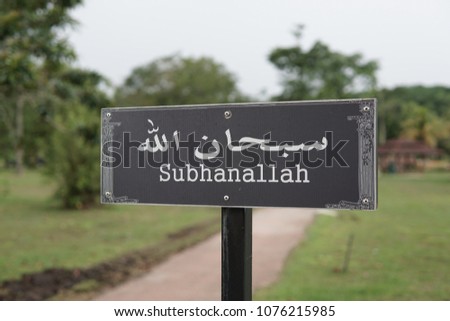 An Arabic verse signpost with background of a park. Subhanallah is an Arabic verse in Islamic practice that means "Glory be to Allah".