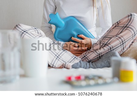 Woman using blue hot water bottle Royalty-Free Stock Photo #1076240678