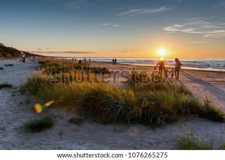 Warm summer sunset. Beach landscape with silhouettes of people on the background. Jurmala resort, Latvia, Baltic Sea. Vacation concept 