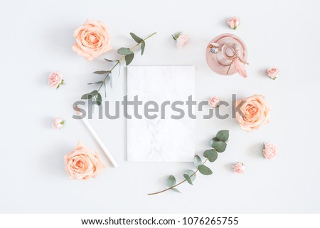 Wedding invitation card. Marble paper blank, rose flowers, eucalyptus branches on gray background. Wedding concept. Flat lay, top view, copy space