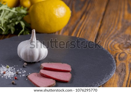 Piece of meat with lemon, garlic on wooden background flat lay
