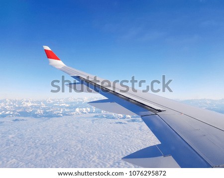 Picture of airplane wing, cloudy sky from porthole