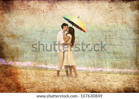 Couple kissing under umbrella at the beach. Photo in old image style.