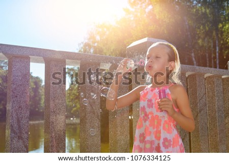 Child blowing soap bubbles. Girl playing outdoors.