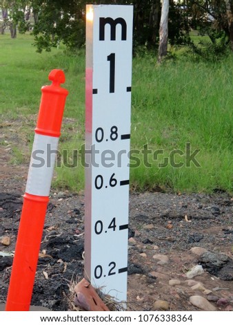 Flood depth warning sign with danger post beside it in Queensland Australia