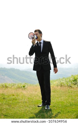 Business man with loudspeaker in nature