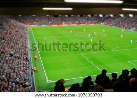 Blurred background of football players playing and soccer fans in match day on beautiful green field with sport light at the stadium. Sports,Athlete,People Concept.Anfield,Mercyside,Liverpool,UK. Royalty-Free Stock Photo #1076350703