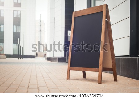 Blank Wooden Sandwich Board at the Street Near skyscrapers. Business Center, Commercial Center, Downtown.  Copy Space, Empty Space for Advertising