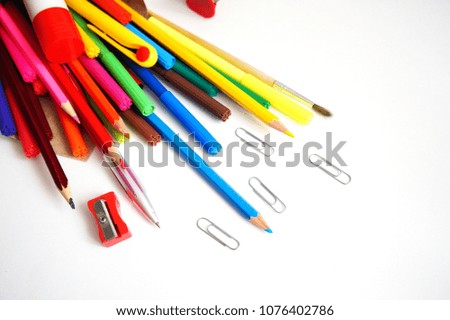 colored pencils, markers, handles, the highlighter, glue, paper clips, the anti-stapler and a sharpener on a white background close up                 