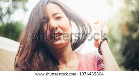 soft focus. happy cheerful young asian woman with sunlight flare.beautiful girl looking at camera with joyful and charming smile relaxing in summer sunset sky outdoor. people freedom style concept