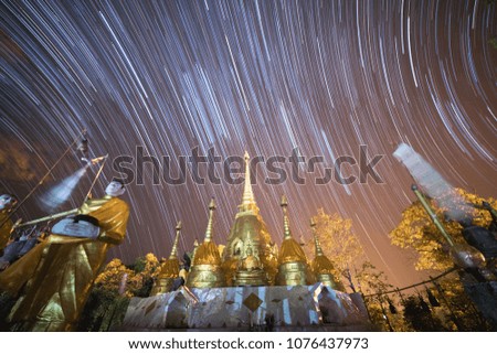 Startrails over the beautiful group of golden pagodas in Buddhist temple in Kanchanaburi, Thailand