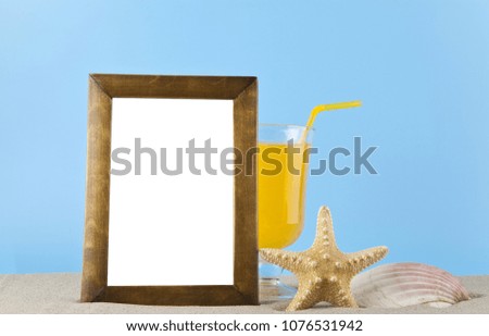 starfish, shell, orange juice and photo frame in the sand for relaxation on a blue background