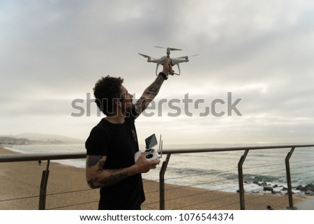Trendy and young amateur professional pilot flies, sets in air big white drone for aerial photography or video surveillance, holds remote control in hands. concept futuristic technology innovation
