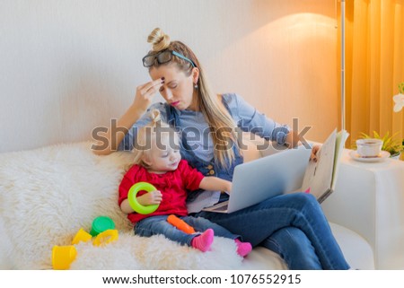 Tired mom trying to work on computer Royalty-Free Stock Photo #1076552915