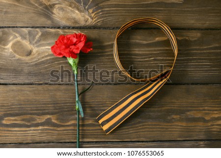 Red flower and St. George ribbon shaped as a nine symbol of world war II on wooden background.