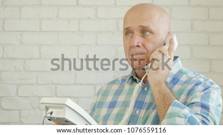 Man in Office Room Stay in Front of a Window Make a Conversation Using Landline