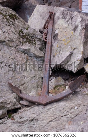old rusty metal anchor sitting against a rock