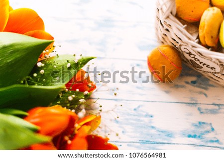 Blossoming tulips with macaroons on a light wooden background. Still life, spring concept