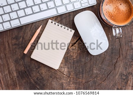 Top view of office stuff with keyboard, mouse, notepad, pencil and cup of coffee on wooden background