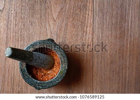 Chili peppers in stone mortar on wooden background. Royalty-Free Stock Photo #1076589125