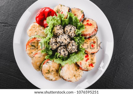 Healthy appetizer, grilled zucchini and eggplant with cheese with cheese on plate over black stone background. Clean eating, vegan food concept. Top view, flat lay