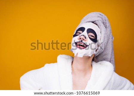 a cute young girl with a towel on her head and in a bathrobe, after a shower she smiles, her face is masked with a dog's face