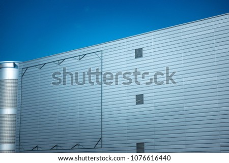 Blank billboard steel frame on facade of industial style building under blue sky