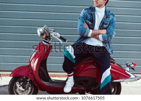 cropped shot of man in stylish old school clothes on vintage red scooter