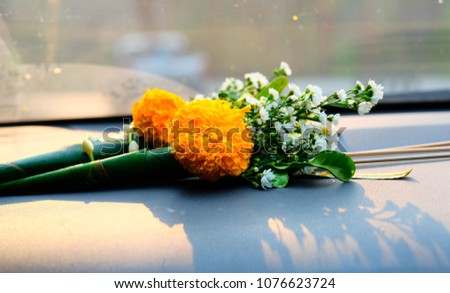 Marigold, flowers, candles and joss sticks in the cone ready for worship is placed on the front of the car.